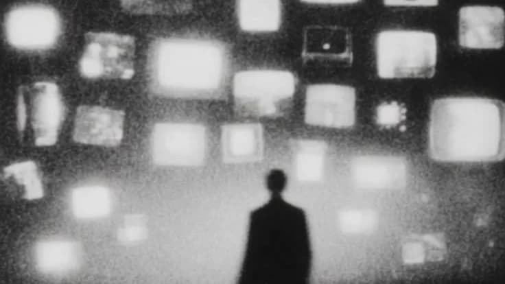 A lone figure in fog facing a wall of old glowing television screens