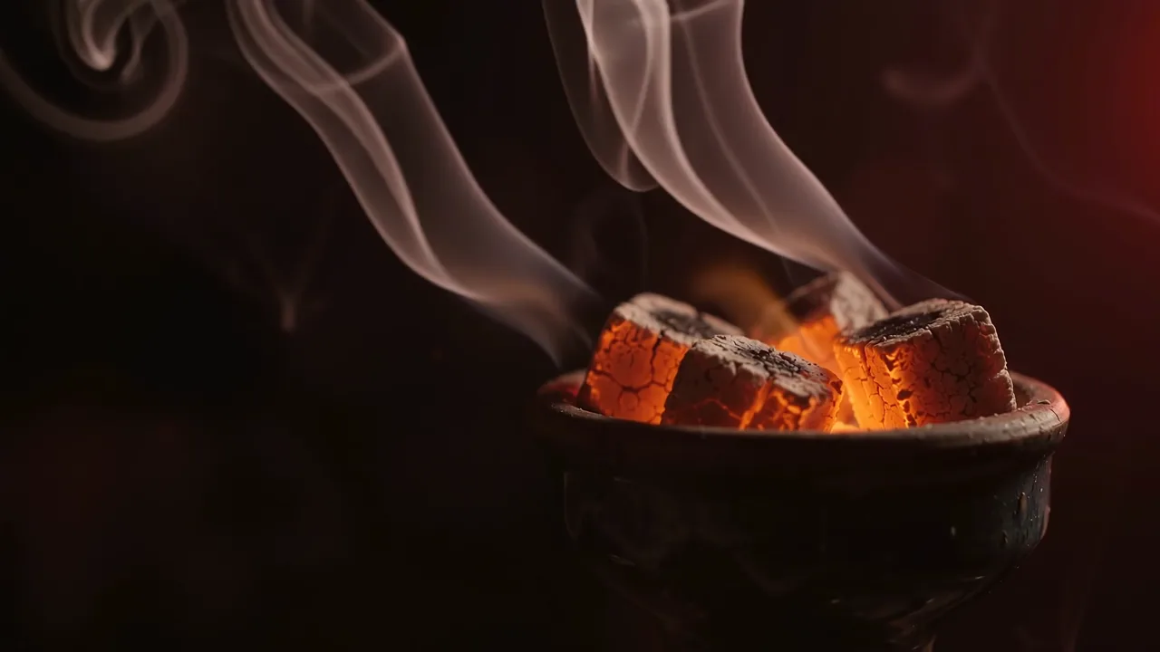 Glowing coals on a hookah bowl with rising smoke